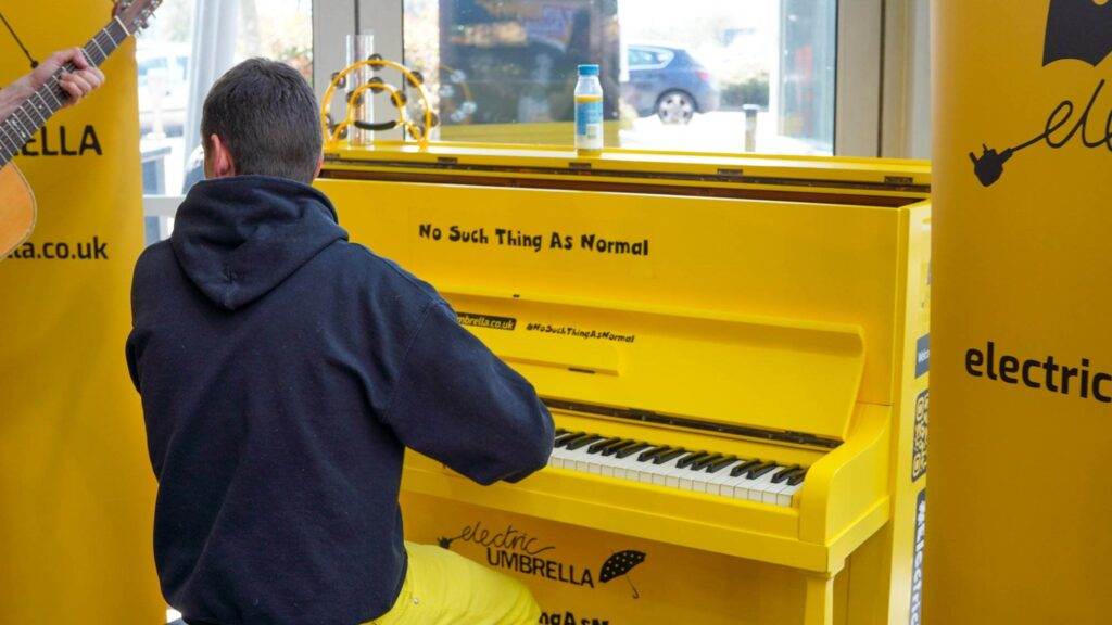 Person playing yellow piano labeled Electric Umbrella.